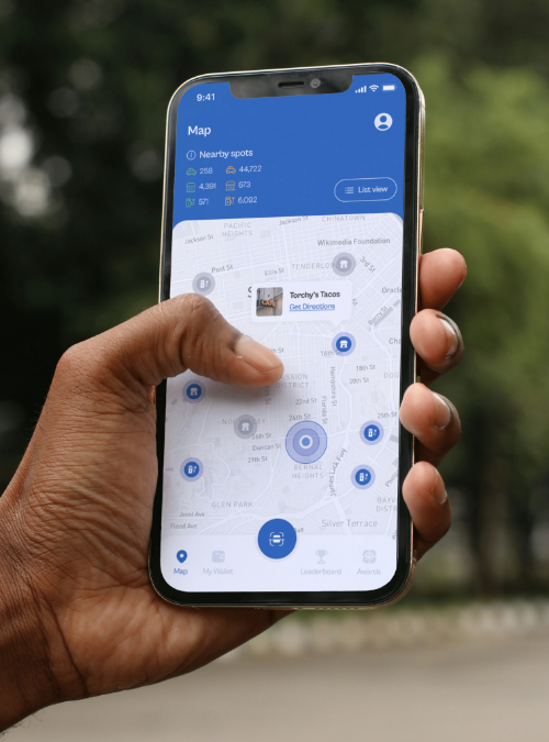 A hand holding a phone with the Avrio USA App displaying an interractive map.